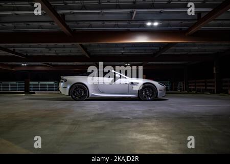 Una bella Aston Martin Vanquish bianco parcheggiato da solo in un garage vuoto e poco illuminato Foto Stock