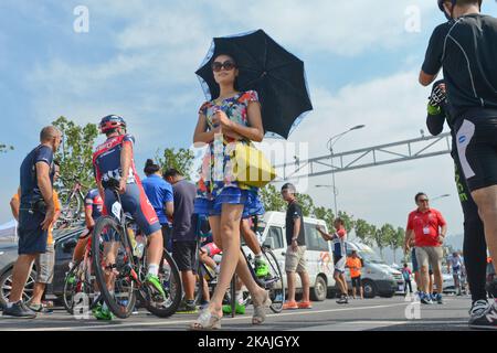 Una signora locale osserva la preparazione dei piloti davanti alla gara di 114,7 km del circuito di Chongqing Banan, durante il 2016 Tour of China 1. Chongqing è una delle principali città del sud-ovest della Cina e una delle cinque città centrali nazionali della Cina (municipalità a controllo diretto). Municipalità a controllo diretto in passato, Chongqing era la capitale della Cina durante la seconda guerra sino-giapponese (seconda guerra mondiale), E dal 1938 al 1946, sede amministrativa del governo della Repubblica di Cina. La tappa si svolge nel distretto di Banan, un distretto del comune di Chongqing. Lunedì 12 settembre 2 Foto Stock