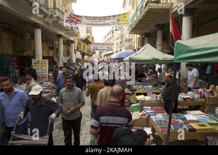 Gli iracheni guardano i libri esposti al di fuori delle librerie sulla via al-Mutanabi nel centro di Baghdad il 29 ottobre 2016. La famosa strada, inaugurata nel 1932 dal re Faisal i e intitolata al principale poeta del 10th° secolo Abu al-Tayyib al-Mutanabi, nato in quello che è ora l'Iraq, è considerata dagli iracheni come un centro intellettuale del mondo arabo, diventando nel corso dei decenni un luogo di incontro per scrittori, artisti e intellettuali di tutta la capitale. (Foto di Noe Falk Nielsen/NurPhoto) *** Please use Credit from Credit Field *** Foto Stock