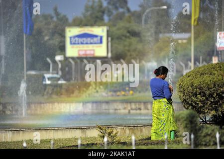 Una donna prende il riposo corto come lavorando nel giardino dell'aeroporto internazionale di Tribhuwan a Kathmandu, Nepal il venerdì 16 dicembre 2016 come l'arcobaleno della fontana dell'acqua vista sullo sfondo. (Foto di Narayan Maharjan/NurPhoto) *** Please use Credit from Credit Field *** Foto Stock