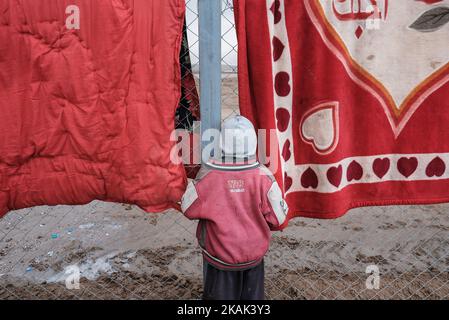 Foto scattata nel campo di Qayyarah Jadah vicino al campo di Qayyarah Jadah il 23 dicembre 2016. Ragazzo in piedi alla recinzione del campo profughi. A due mesi dall'operazione militare per riconsiderare la città dallo Stato islamico dell'Iraq e dal Levante (ISIL), la crisi di Mosul continua ad avere un impatto umanitario significativo. I bisogni umanitari sono gravi tra le famiglie sfollate dentro e fuori dai campi, i vulnerabili residenti delle comunità appena ritirate e le persone che fuggono dai combattimenti nella città di Mosul. Lo sfollamento attuale è salito a 110.000 persone. Più di tre quarti delle famiglie sfollate si trovano nei campi e nei luoghi di emergenza, w Foto Stock