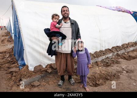 Foto scattata nel campo di Qayyarah Jadah vicino al campo di Qayyarah Jadah il 23 dicembre 2016. Il sig. Zeki Abdoullah che tiene la figlia Aida e Raqat sfollati dalla provincia di Niniveh . A due mesi dall'operazione militare per riconsiderare la città dallo Stato islamico dell'Iraq e dal Levante (ISIL), la crisi di Mosul continua ad avere un impatto umanitario significativo. I bisogni umanitari sono gravi tra le famiglie sfollate dentro e fuori dai campi, i vulnerabili residenti delle comunità appena ritirate e le persone che fuggono dai combattimenti nella città di Mosul. Lo sfollamento attuale è salito a 110.000 persone. Più di tre quarti della disp Foto Stock