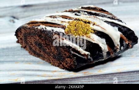 Un rotolo svizzero di torta al cioccolato, combinazione di una leggera torta di Spagna al cioccolato con panna montata alla vaniglia dolce e un dessert di ganache al cioccolato, coperto w Foto Stock