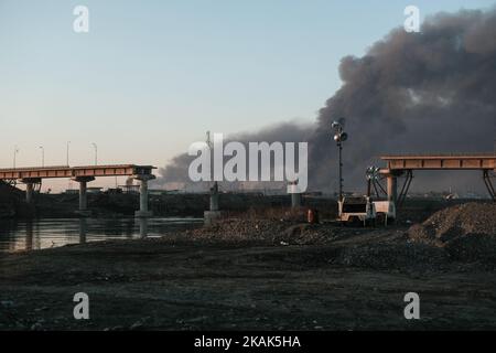 Crisi umanitaria vicino a Mosul in Iraq. Foto scattata a Qayyarah il 03 gennaio 2017. Ponte distrutto dalla coalizione Airstrike Area di Jadah Camp è influenzato da nube di fumo scuro e fuliggine da bruciare campi di petrolio in cui ISIL ha impostato Fire.The principale preoccupazione, secondo Oxfam, È che il fumo dai pozzi di petrolio causerà bronchite tra una popolazione che ha accesso a scarsa medicina.due mesi nell'operazione militare per ricontrarsi la città dallo Stato islamico dell'Iraq e del Levante (ISIL), la crisi di Mosul continua ad avere un impatto umanitario significativo. I bisogni umanitari sono gravi tra le disgrazie Foto Stock