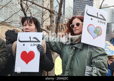 Le donne hanno dei segnali in inglese e arabo che dicono 'Amore' mentre migliaia di canadesi prendono parte a una massiccia protesta contro il divieto di viaggio del presidente Trump ai musulmani durante la Giornata nazionale d'azione contro l'islamofobia e la supremazia bianca nel centro di Toronto, Ontario, Canada, il 04 febbraio 2017. I canadesi si sono Uniti a paesi di tutto il mondo nel protestare contro l'ordine esecutivo del presidente americano Donald Trump, vietando i cittadini di sette paesi musulmani a maggioranza (Iran, Iraq, Sudan, Somalia, Siria, Yemen e Libia) di entrare negli Stati Uniti per i prossimi tre mesi e di vietare i rifugiati siriani Foto Stock