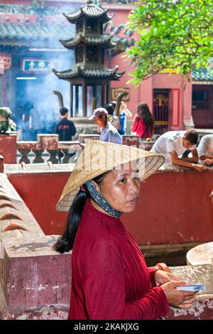 Donna vietnamita che indossa un cappello di bambù di fronte alla Pagoda dell'Imperatrice di Giada, ho Chi Minh City, Vietnam Foto Stock