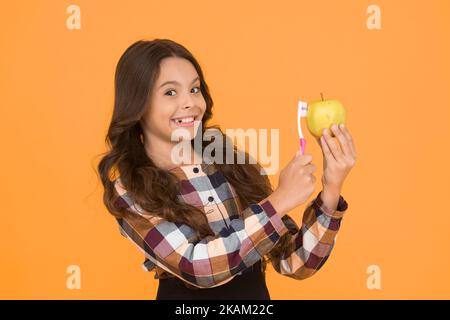 Igiene orale. Ragazza cute tenere spazzolino da denti e mela. Bambina tenere il dente pennello con pasta. Bambino ragazza felice igiene di cura del viso. Concetto di igiene Foto Stock