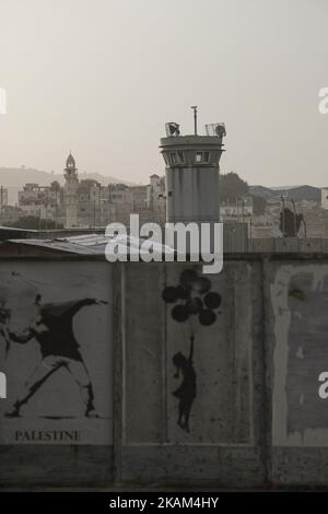 Le opere d'arte di Banksy sono visibili su un muro di fronte a una torre di guardia, vicino al 'Walled Off Hotel' dell'artista di strada britannico Banksy, che si trova proprio di fronte al muro di separazione di Israele, il 11 marzo 2017, a Betlemme, in Cisgiordania. (Foto di Corinna Kern/NurPhoto) *** Please use Credit from Credit Field *** Foto Stock