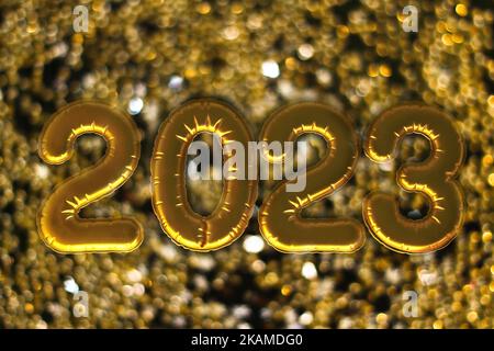 Palloncini gonfiabili d'oro numero 2023 sulla finestra sullo sfondo della città notturna, in luce al neon. Capodanno 2023, natale. Natale e Capodanno 2023. Foto Stock