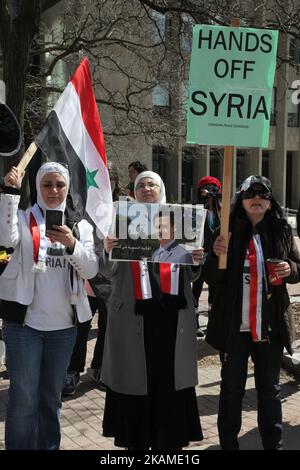 La donna siriana ha in mano un poster del presidente siriano Bashar al-Assad durante una protesta contro la decisione del presidente americano Donald Trump di lanciare attacchi aerei contro la Siria il 8 aprile 2017 a Toronto, Ontario, Canada. I manifestanti si sono riuniti al di fuori del Consolato americano di Toronto per denunciare le scioperi aerei di questa settimana contro il regime siriano. L’America ha lanciato uno sciopero missilistico contro la Siria per la prima volta dall’inizio della guerra civile, puntando su una base aerea nella piccola città di Idlib da cui gli Stati Uniti sostengono che l’attacco di armi chimiche contro i civili di questa settimana è stato lanciato dal regime di Bashar al-Assad Foto Stock