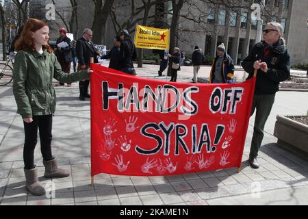 I dimostranti hanno una bandiera che dice "mani libere dalla Siria" durante una protesta contro la decisione del presidente degli Stati Uniti Donald Trump di lanciare attacchi aerei contro la Siria il 8 aprile 2017 a Toronto, Ontario, Canada. I manifestanti si sono riuniti al di fuori del Consolato americano di Toronto per denunciare le scioperi aerei di questa settimana contro il regime siriano. L’America ha lanciato uno sciopero missilistico contro la Siria per la prima volta dall’inizio della guerra civile, puntando su una base aerea nella piccola città di Idlib da cui gli Stati Uniti sostengono che l’attacco di armi chimiche contro i civili di questa settimana è stato lanciato dal regime di Bashar al-Assad. (Foto di Foto Stock