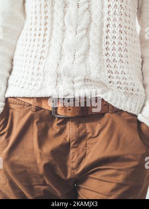Donna in maglia bianca con pattinatore scandinavo e pantaloni chino marroni con cintura in pelle. Abbigliamento casual per il tempo. urb moderna Foto Stock