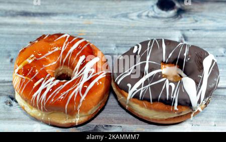 Ciambelle ad anello con salsa di cioccolato marrone, caramello e bianco, Una glassata, lievitata, ciambelle ad anello stile americano, tipo di cibo fatto da lievitato profondo Foto Stock