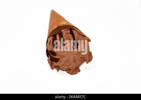 Pallina di gelato alla vaniglia al cioccolato su un cono di biscotto con salsa di cioccolato isolata su fondo bianco, fuoco selettivo del cono di gelato marrone scuro wit Foto Stock