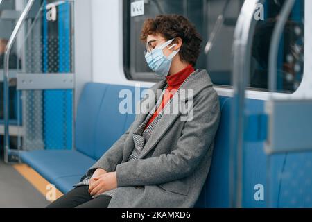 donna stanca in una maschera protettiva si addormentò in una macchina della metropolitana . Foto Stock