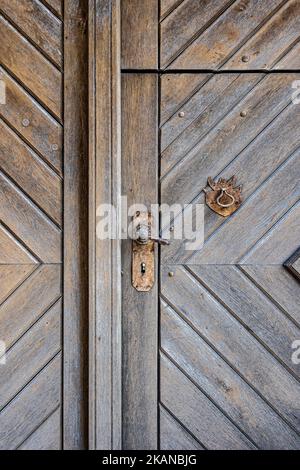 Vecchia porta in legno con maniglia e batticalcagno arrugginiti Foto Stock