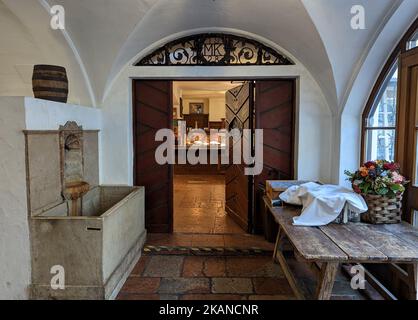 L'ingresso in legno di una birreria e di una fontana d'acqua, bicchieri coperti di stoffa su un tavolo in Berchtesgaden Foto Stock