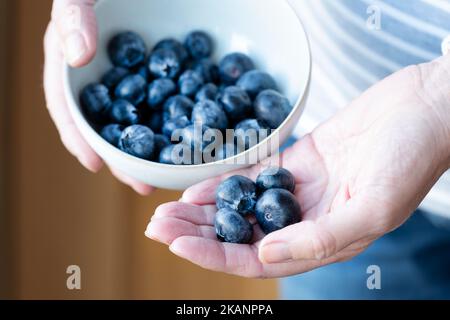 Una donna che detiene una dose giornaliera raccomandata di mirtilli. La misura della porzione è 150g o una tazza. Gli antiossidanti sani sono ricchi di vitamine Foto Stock