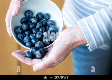 Una donna che detiene una dose giornaliera raccomandata di mirtilli. La misura della porzione è 150g o una tazza. Gli antiossidanti sani sono ricchi di vitamine Foto Stock