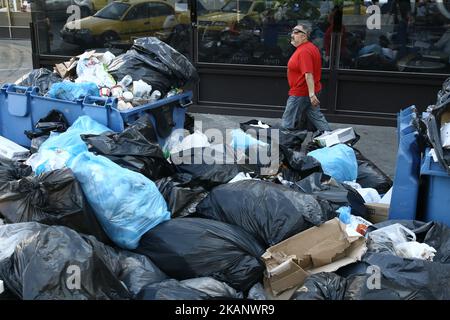 Un uomo pasi di fronte alla spazzatura in piazza Omonia, nel centro di Atene il 23 giugno 2017. Mucchi di rifiuti si accumulano intorno a cassoni traboccanti ad Atene, in seguito a ripetuti scioperi chiamati dalla Federazione dei lavoratori nei comuni che richiedono l'assunzione permanente di circa 10.000 lavoratori a contratto i cui contratti sono scaduti (Foto di Panayotis Tzamaros/NurPhoto) *** Please use Credit from Credit Field *** Foto Stock