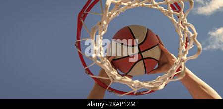 le mani del giocatore di basket gettano la palla nel cerchio, successo. Design poster orizzontale. Intestazione banner Web, spazio di copia. Foto Stock