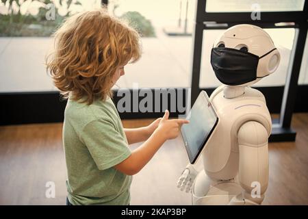 il bambino occupato interagisce con l'intelligenza artificiale del robot, la comunicazione Foto Stock