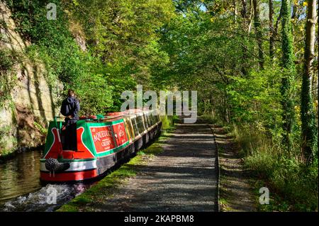 Le persone che si godono un viaggio su un narrowboat nel sole tardo autunno sul canale di Llangollen a Clwyd, Galles anche all'inizio di novembre molte delle foglie sono ancora di colore. Foto Stock