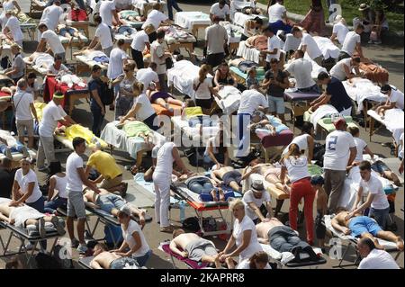 300 massaggiatori e massaggiatori ucraini eseguono un massaggio simultaneo nel tentativo di rompere il Guinness World Record per il massaggio, vicino all'Arco dell'amicizia delle nazioni a Kiev, Ucraina, 27 agosto, 2017. Il registro nazionale dei record ha registrato il record dell'Ucraina come 'il maggior numero di massaggiatori, che eseguono il massaggio simultaneo'. (Foto di Str/NurPhoto) Foto Stock