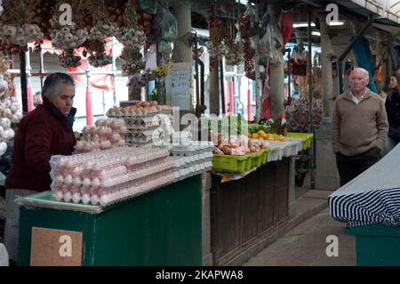 Una vecchia signora che vende uova in un mercato con un vecchio di passaggio a Porto città Portogallo Foto Stock