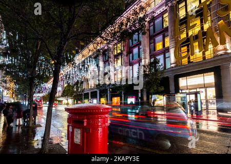 Natale 2022 come le luci sono accese con una vista attraverso la trafficata oxford Street a Selfridges.in primo piano è una casella postale rossa e un taxi. Foto Stock