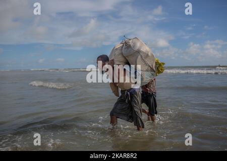 Rohingya rifugiato che carring le sue famiglie e camminare verso la riva del Bangladesh dopo aver attraversato il fiume NaF in barca. Shahpirer DIP, Teknaf, Bangladesh; 14 settembre 2017. Il Bangladesh utilizzerà le truppe per fornire aiuti esteri alla città di confine che è stata sopraffatta dai rifugiati musulmani di Rohingya provenienti dal Myanmar, le autorità hanno annunciato la fine di settembre 14. La mossa fa seguito alle critiche sulle condizioni caotiche in cui le forniture di soccorso sono state distribuite negli enormi campi intorno al Bazar di Cox, dove circa 389.000 Rohingya dallo stato di Rakhine del Myanmar sono arrivati dall'agosto 25. (Foto di Turjoy Chowdhury/N Foto Stock