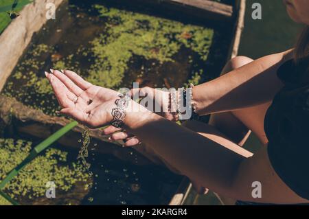 Piccola lumaca nelle mani della donna con braccialetti alla luce del sole Foto Stock