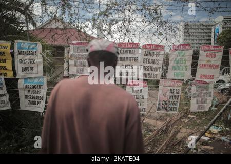 Un uomo dello Zimbabwe legge i giornali appesi in una strada nella capitale Harare, Zimbawe, il 20 novembre 2017. I giornali sono tenuti giù dalle rocce per impedirli di sparare via ad un'edicola ad Harare, Zimbabwe Lunedi, 20 novembre 2017. Il presidente di lunga data Robert Mugabe ha ignorato una scadenza fissata dal partito al governo per dimettersi o affrontare i procedimenti di impeachment, mentre gli abitanti dello Zimbabwe hanno stordito per la sua mancanza di dimissioni durante un discorso nazionale hanno promesso ulteriori proteste per fargli uscire. (Foto di Belal Khaled/NurPhoto) Foto Stock
