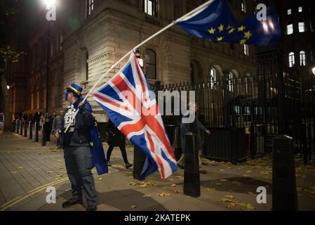 Un dimostratore anti-Brexit sventola la bandiera dell’UE e quella dell’Unione, al di fuori di Downing Street, Londra, il 21 novembre 2017. La protesta si è svolta la sera prima del giorno del bilancio. Nel Regno Unito, la giornata del bilancio è il giorno in cui il Cancelliere dello scacchiere consegna il bilancio al Gabinetto e poi alla Camera dei Comuni. (Foto di Alberto Pezzali/NurPhoto) Foto Stock
