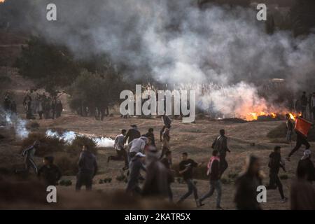 I manifestanti palestinesi si coprono del gas lacrimogeno israeliano durante una protesta contro la decisione del presidente americano Trump di riconoscere Gerusalemme come capitale d'Israele, durante gli scontri lungo il confine tra Israele e la striscia di Gaza orientale, a est del campo profughi di al Bureij, il 08 dicembre 2017. Il Presidente DEGLI STATI UNITI Donald J. Trump ha annunciato il 06 dicembre che gli Stati Uniti riconoscono Gerusalemme come capitale israeliana e che trasferiranno la propria ambasciata da Tel Aviv a Gerusalemme. Due manifestanti palestinesi sono stati uccisi e altri 56 sono stati feriti dopo essere stati uccisi dai soldati israeliani durante gli scontri contro la d Foto Stock