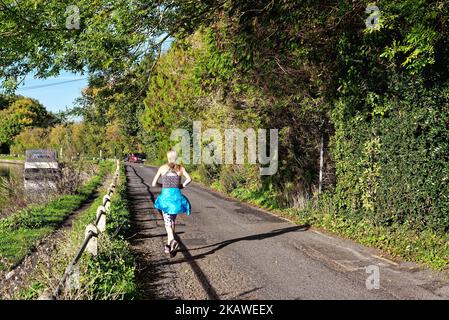 Vista posteriore di un'attraente giovane ragazza bionda runner sul sentiero che corre lungo il Tamigi in un giorno d'autunno a Shepperton Surrey Inghilterra UK Foto Stock
