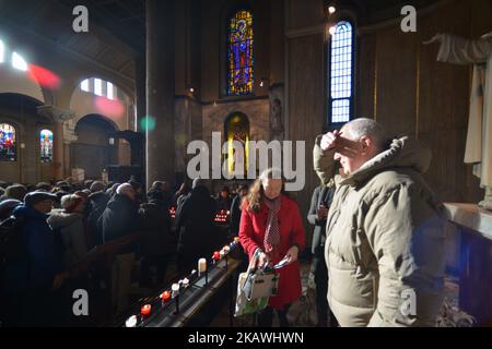 Una vista della folla nella cappella con la statua del santo patrono dell'amore, San Valentino, all'interno della chiesa di Whitefriar a Dublino. San Valentino, patrono dell'amore, fu giustiziato e sepolto a Roma il 14 febbraio 269. Più tardi, nel 1835, un sacerdote carmelitano irlandese, P. John Spratt, ha usato il suo fascino irlandese per convincere Papa Gregorio XVI ad esumare i resti di San Valentino e a portarlo in Irlanda come dono ai suoi compagni Irishmen e alle sue donne. Da allora, lo scheletro di San Valentino si trova sotto la chiesa di Whitefriar a Dublino. Nel 1950, una statua e un santuario sono stati costruiti per onorare San Valentino e collocati nella chiesa. Amore-seeki Foto Stock