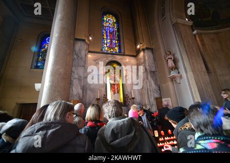 Una vista della folla nella cappella con la statua del santo patrono dell'amore, San Valentino, all'interno della chiesa di Whitefriar a Dublino. San Valentino, patrono dell'amore, fu giustiziato e sepolto a Roma il 14 febbraio 269. Più tardi, nel 1835, un sacerdote carmelitano irlandese, P. John Spratt, ha usato il suo fascino irlandese per convincere Papa Gregorio XVI ad esumare i resti di San Valentino e a portarlo in Irlanda come dono ai suoi compagni Irishmen e alle sue donne. Da allora, lo scheletro di San Valentino si trova sotto la chiesa di Whitefriar a Dublino. Nel 1950, una statua e un santuario sono stati costruiti per onorare San Valentino e collocati nella chiesa. Amore-seeki Foto Stock