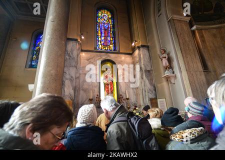 Una vista della folla nella cappella con la statua del santo patrono dell'amore, San Valentino, all'interno della chiesa di Whitefriar a Dublino. San Valentino, patrono dell'amore, fu giustiziato e sepolto a Roma il 14 febbraio 269. Più tardi, nel 1835, un sacerdote carmelitano irlandese, P. John Spratt, ha usato il suo fascino irlandese per convincere Papa Gregorio XVI ad esumare i resti di San Valentino e a portarlo in Irlanda come dono ai suoi compagni Irishmen e alle sue donne. Da allora, lo scheletro di San Valentino si trova sotto la chiesa di Whitefriar a Dublino. Nel 1950, una statua e un santuario sono stati costruiti per onorare San Valentino e collocati nella chiesa. Amore-seeki Foto Stock