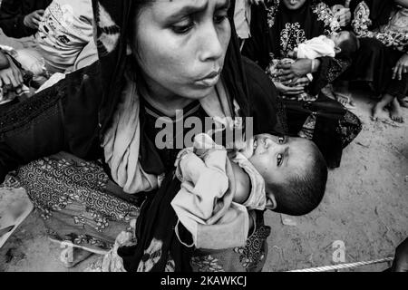 La donna rifugiata Rohingya tiene il suo bambino in attesa di assistenza medica in una clinica sul campo da parte dell'organizzazione non governativa Mercy Malaysia al campo profughi di Thankhali vicino a Cox's Bazar, Bangladesh, 24 novembre 2017. (Foto di Szymon Barylski/NurPhoto) Foto Stock