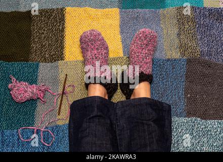 Donna piedi indossando calde pantofole fatte a mano in lana accanto al crochet ago e filo, crochet e maglieria come un hobby Foto Stock