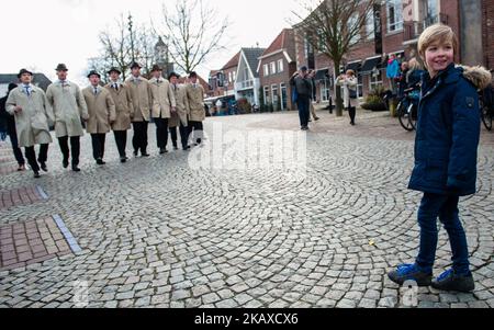 Aprile 1st, Ootmarsum. I poaskearls (uomini di Pasqua in un dialetto olandese) sono giovani cattolici singoli di Ootmarsum e si esibiscono annualmente in un tradizionale evento intorno a Pasqua chiamato 'vlöggeln' cantando antichi inni medievali. Il più vecchio degli otto uomini è tradizionalmente fumare un sigaro e come proprietario della finanza è soprannominato Judas. Ogni anno vengono scelti due nuovi poaskearl che sostituiscono i due più vecchi. Si snodano per le strade, attingendo ai fondamenti delle vecchie fattorie e passando da diversi caffè. I Poaskearls sono giovani cattolici di Ootmarsum che indossano un lungo colò beige Foto Stock