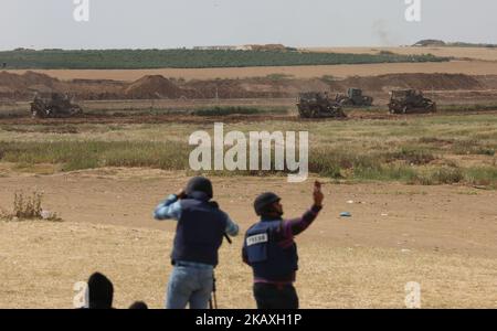 I palestinesi guardano al meccanismo militare israeliano che lavora al confine tra Israele e la striscia di Gaza, alla periferia di Gaza City, il 11 aprile 2018. L'esercito israeliano ha dichiarato di aver sparato contro "obiettivi militari" di Hamas non specificati a Gaza dopo un attacco di bomba palestinese contro un'unità di ingegneria dell'esercito che opera all'interno del territorio governato da Hamas. Nessun israeliano è stato riportato ferito nell'esplosione, che la stazione radio dell'esercito ha detto di aver preso di mira un scavatore meccanico. (Foto di Majdi Fathi/NurPhoto) Foto Stock