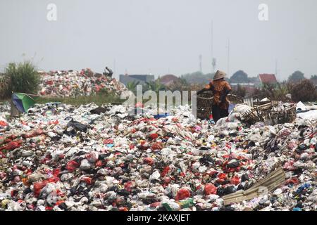 I sequestratori risolvono i rifiuti di plastica riciclabili a discariche illegali sulle rive del fiume CBL, distretto di Bekasi, Bekasi, Giava Occidentale sabato 14 aprile 2018. Con una popolazione di 2,4 milioni di persone, Bekasi come città satellite per Giacarta, si trova ad affrontare gravi problemi legati al trattamento dei rifiuti, che ha raggiunto le 1.700 tonnellate al giorno. In base ai dati dell'Agenzia per l'ambiente di Kota Bekasi, solo 600 tonnellate di rifiuti possono essere trasportate in discarica, mentre le restanti 1.100 tonnellate vengono smaltite in discariche illegali, come nei pressi di insediamenti o lungo il fiume. (Foto di Aditya Irawan/NurPhoto) Foto Stock