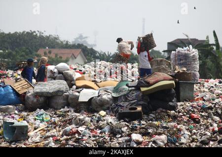 I sequestratori risolvono i rifiuti di plastica riciclabili a discariche illegali sulle rive del fiume CBL, distretto di Bekasi, Bekasi, Giava Occidentale sabato 14 aprile 2018. Con una popolazione di 2,4 milioni di persone, Bekasi come città satellite per Giacarta, si trova ad affrontare gravi problemi legati al trattamento dei rifiuti, che ha raggiunto le 1.700 tonnellate al giorno. In base ai dati dell'Agenzia per l'ambiente di Kota Bekasi, solo 600 tonnellate di rifiuti possono essere trasportate in discarica, mentre le restanti 1.100 tonnellate vengono smaltite in discariche illegali, come nei pressi di insediamenti o lungo il fiume. (Foto di Aditya Irawan/NurPhoto) Foto Stock