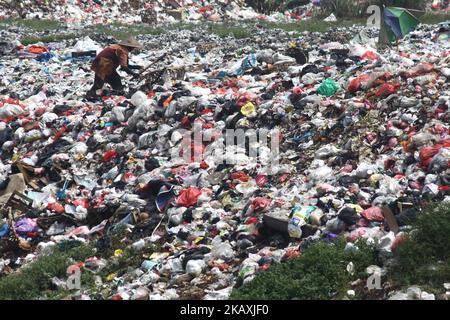 I sequestratori risolvono i rifiuti di plastica riciclabili a discariche illegali sulle rive del fiume CBL, distretto di Bekasi, Bekasi, Giava Occidentale sabato 14 aprile 2018. Con una popolazione di 2,4 milioni di persone, Bekasi come città satellite per Giacarta, si trova ad affrontare gravi problemi legati al trattamento dei rifiuti, che ha raggiunto le 1.700 tonnellate al giorno. In base ai dati dell'Agenzia per l'ambiente di Kota Bekasi, solo 600 tonnellate di rifiuti possono essere trasportate in discarica, mentre le restanti 1.100 tonnellate vengono smaltite in discariche illegali, come nei pressi di insediamenti o lungo il fiume. (Foto di Aditya Irawan/NurPhoto) Foto Stock