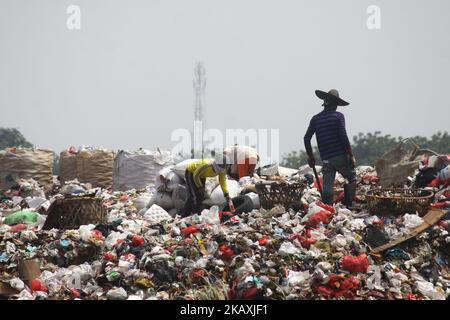 I sequestratori risolvono i rifiuti di plastica riciclabili a discariche illegali sulle rive del fiume CBL, distretto di Bekasi, Bekasi, Giava Occidentale sabato 14 aprile 2018. Con una popolazione di 2,4 milioni di persone, Bekasi come città satellite per Giacarta, si trova ad affrontare gravi problemi legati al trattamento dei rifiuti, che ha raggiunto le 1.700 tonnellate al giorno. In base ai dati dell'Agenzia per l'ambiente di Kota Bekasi, solo 600 tonnellate di rifiuti possono essere trasportate in discarica, mentre le restanti 1.100 tonnellate vengono smaltite in discariche illegali, come nei pressi di insediamenti o lungo il fiume. (Foto di Aditya Irawan/NurPhoto) Foto Stock