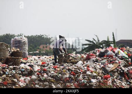 I sequestratori risolvono i rifiuti di plastica riciclabili a discariche illegali sulle rive del fiume CBL, distretto di Bekasi, Bekasi, Giava Occidentale sabato 14 aprile 2018. Con una popolazione di 2,4 milioni di persone, Bekasi come città satellite per Giacarta, si trova ad affrontare gravi problemi legati al trattamento dei rifiuti, che ha raggiunto le 1.700 tonnellate al giorno. In base ai dati dell'Agenzia per l'ambiente di Kota Bekasi, solo 600 tonnellate di rifiuti possono essere trasportate in discarica, mentre le restanti 1.100 tonnellate vengono smaltite in discariche illegali, come nei pressi di insediamenti o lungo il fiume. (Foto di Aditya Irawan/NurPhoto) Foto Stock