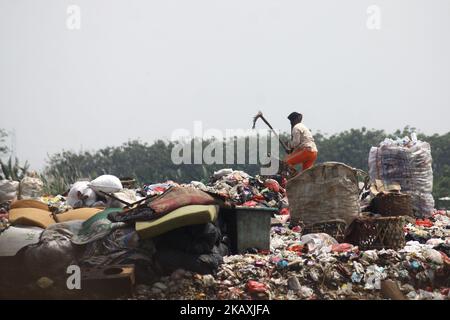 I sequestratori risolvono i rifiuti di plastica riciclabili a discariche illegali sulle rive del fiume CBL, distretto di Bekasi, Bekasi, Giava Occidentale sabato 14 aprile 2018. Con una popolazione di 2,4 milioni di persone, Bekasi come città satellite per Giacarta, si trova ad affrontare gravi problemi legati al trattamento dei rifiuti, che ha raggiunto le 1.700 tonnellate al giorno. In base ai dati dell'Agenzia per l'ambiente di Kota Bekasi, solo 600 tonnellate di rifiuti possono essere trasportate in discarica, mentre le restanti 1.100 tonnellate vengono smaltite in discariche illegali, come nei pressi di insediamenti o lungo il fiume. (Foto di Aditya Irawan/NurPhoto) Foto Stock