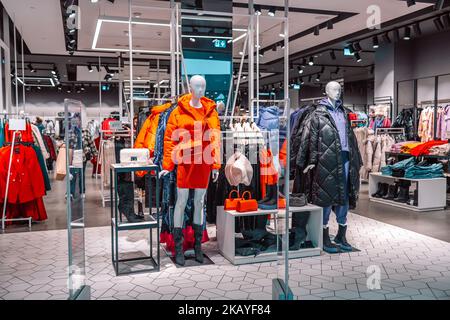 Negozio di abbigliamento per uomo e donna. Manichini vestiti con abiti da donna eleganti e luminosi invernali in un negozio commerciale. Foto Stock